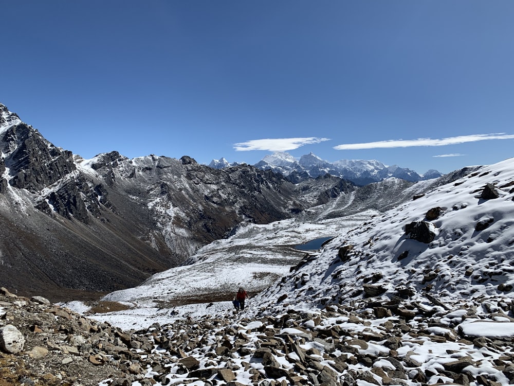 a man hiking up a snowy mountain with mountains in the background