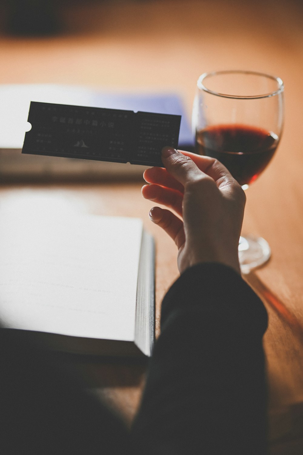 a person holding a business card next to a glass of wine