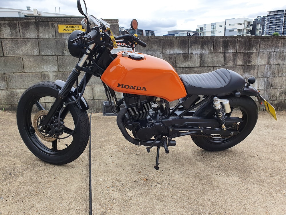 an orange and black motorcycle parked in a parking lot