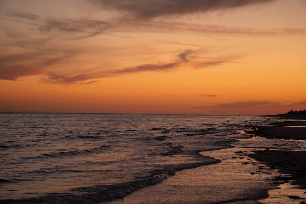 a sunset over the ocean with waves coming in