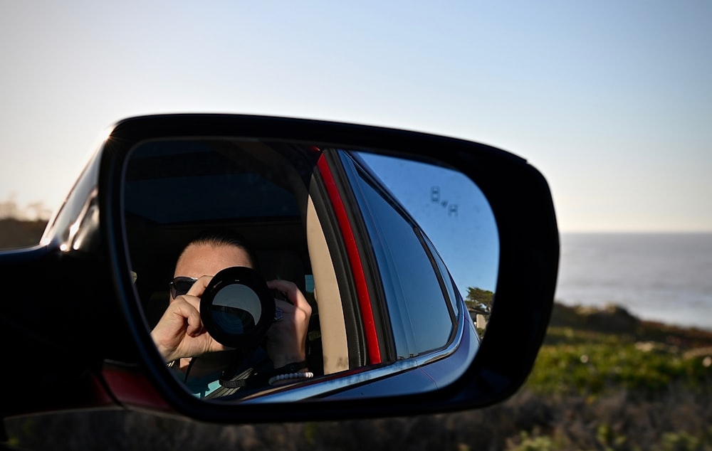 um homem tirando uma foto de si mesmo no espelho lateral de um carro