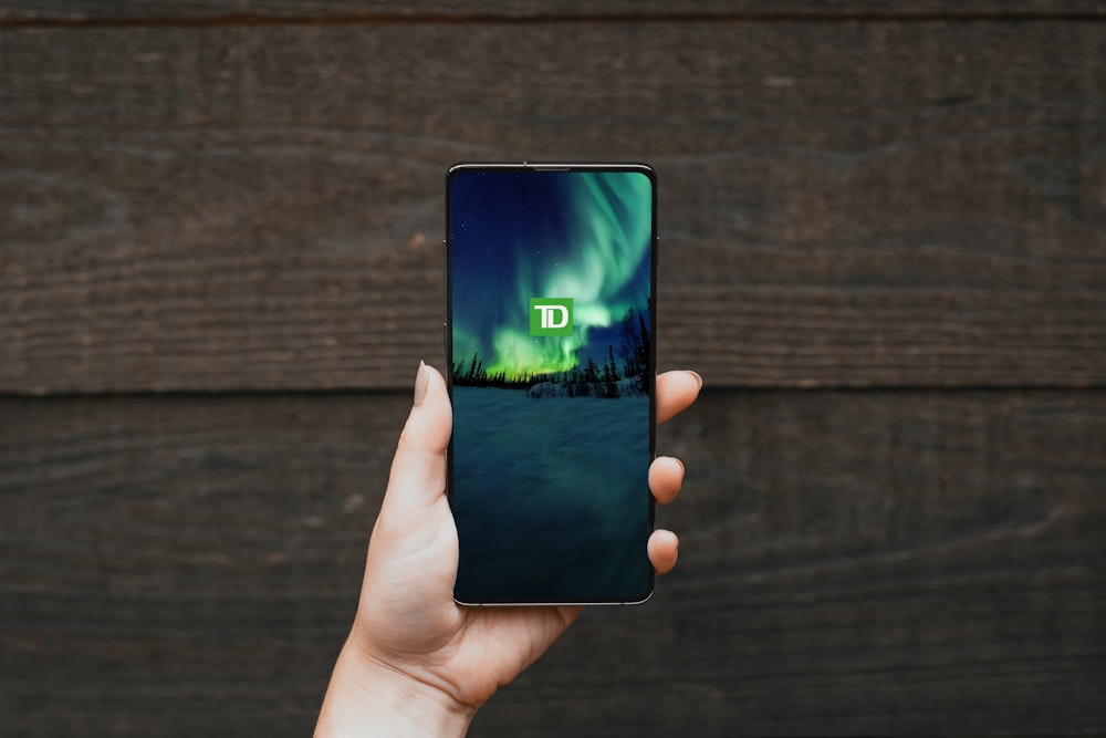 une personne tenant un téléphone cellulaire avec un écran vert
