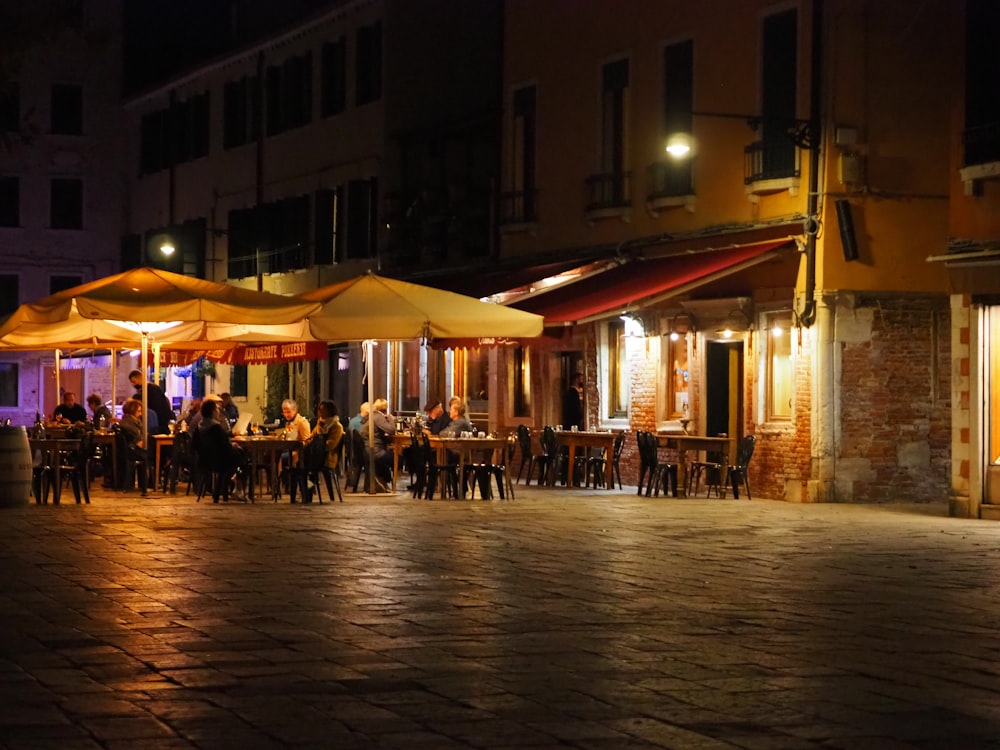 a group of people sitting at tables under umbrellas