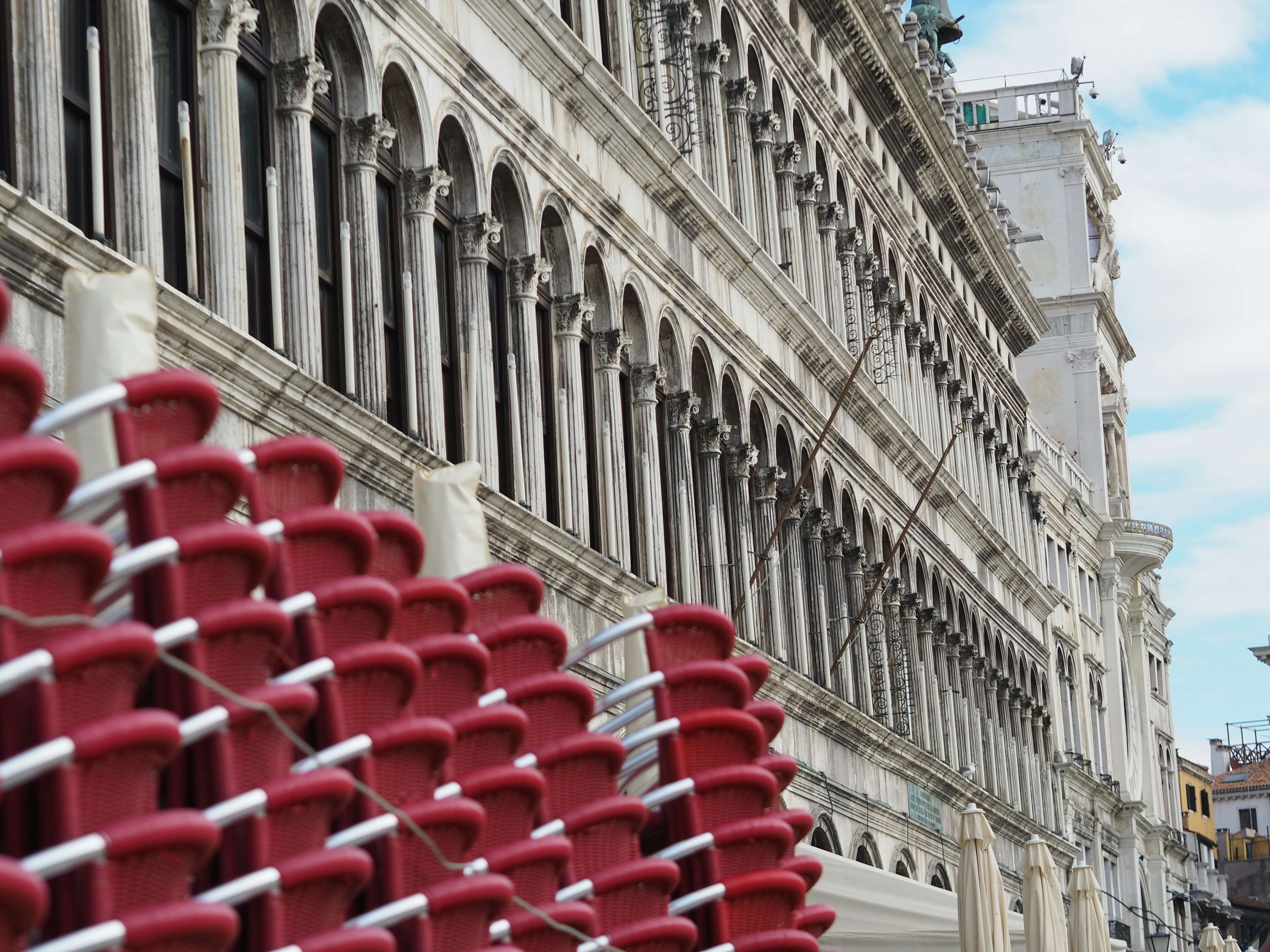 a row of red chairs sitting next to a tall building