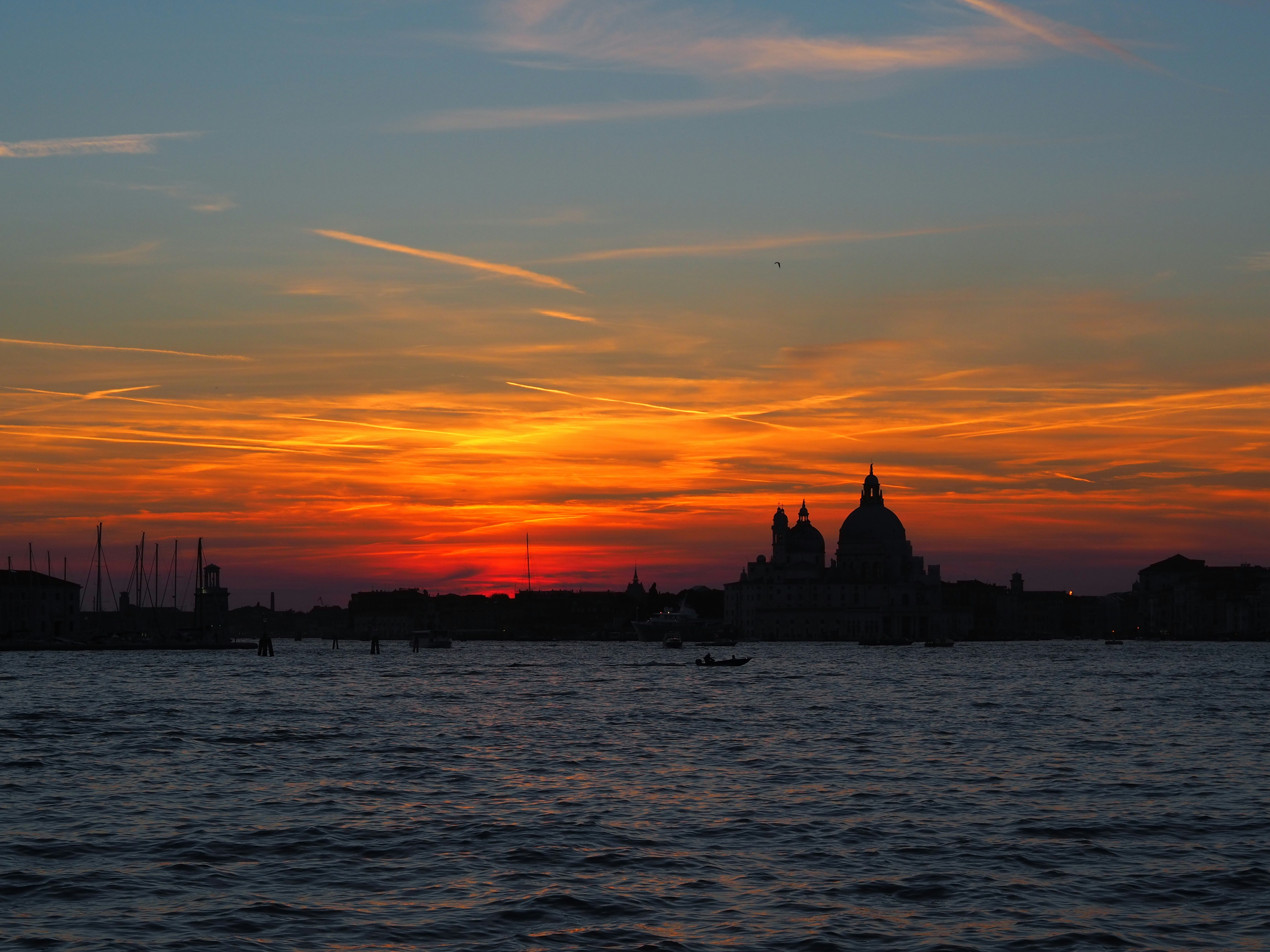 a sunset over a body of water with buildings in the background