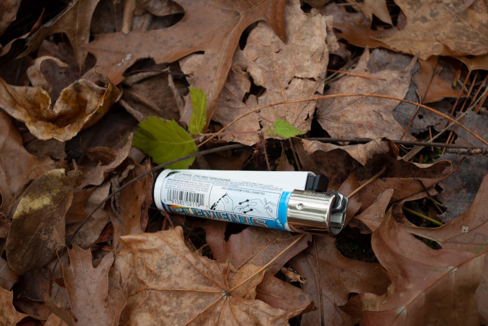 a tube of toothpaste sitting on top of a pile of leaves