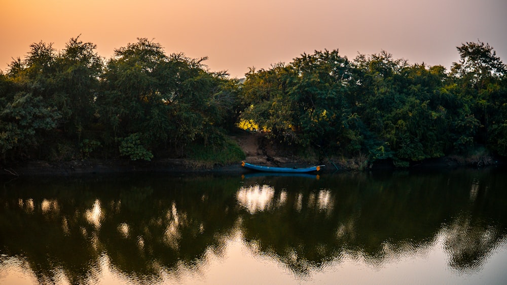 a small boat floating on top of a lake surrounded by trees