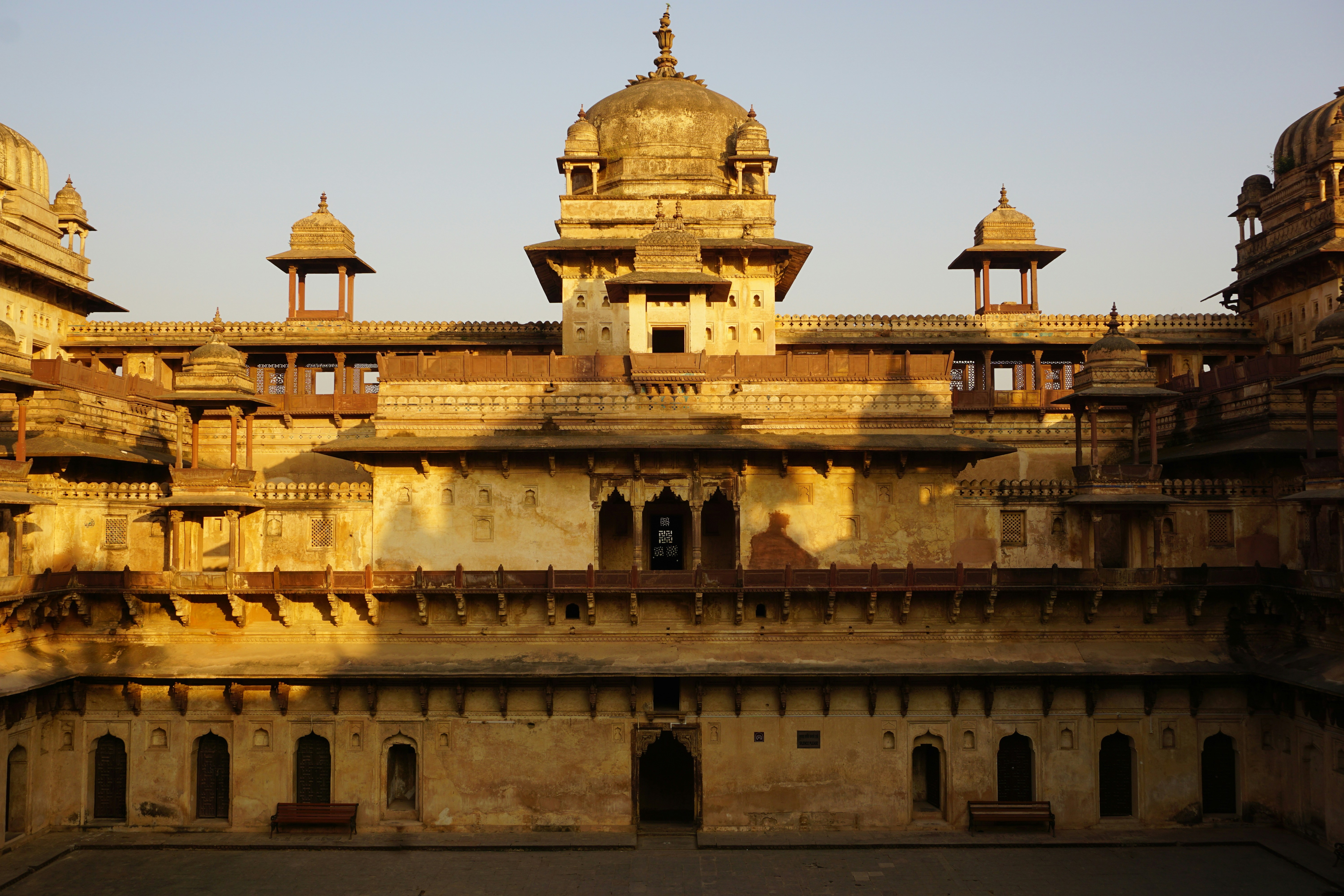 Aerial view of grand Rajasthani palace at golden hour, warm amber light, desert landscape, majestic architecture