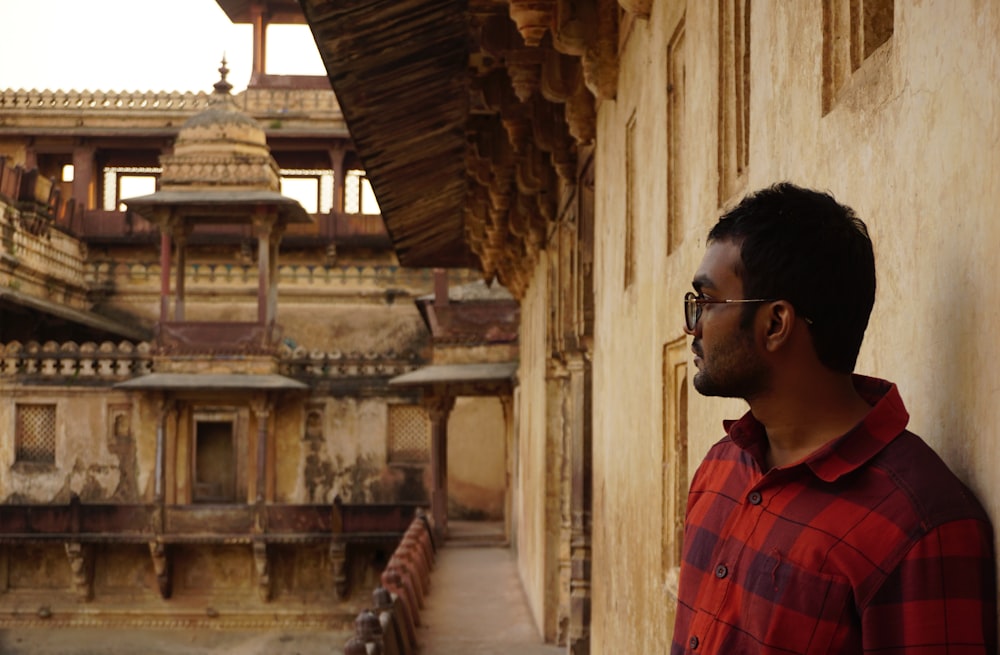 a man leaning against a wall in front of a building