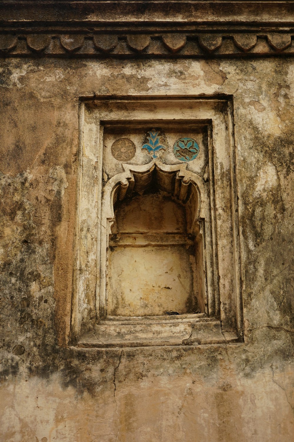 an old building with a window with a flower decoration on it