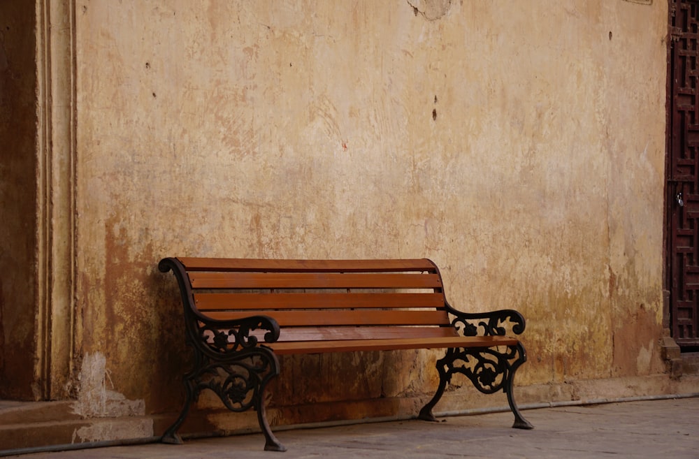 a wooden bench sitting next to a wall