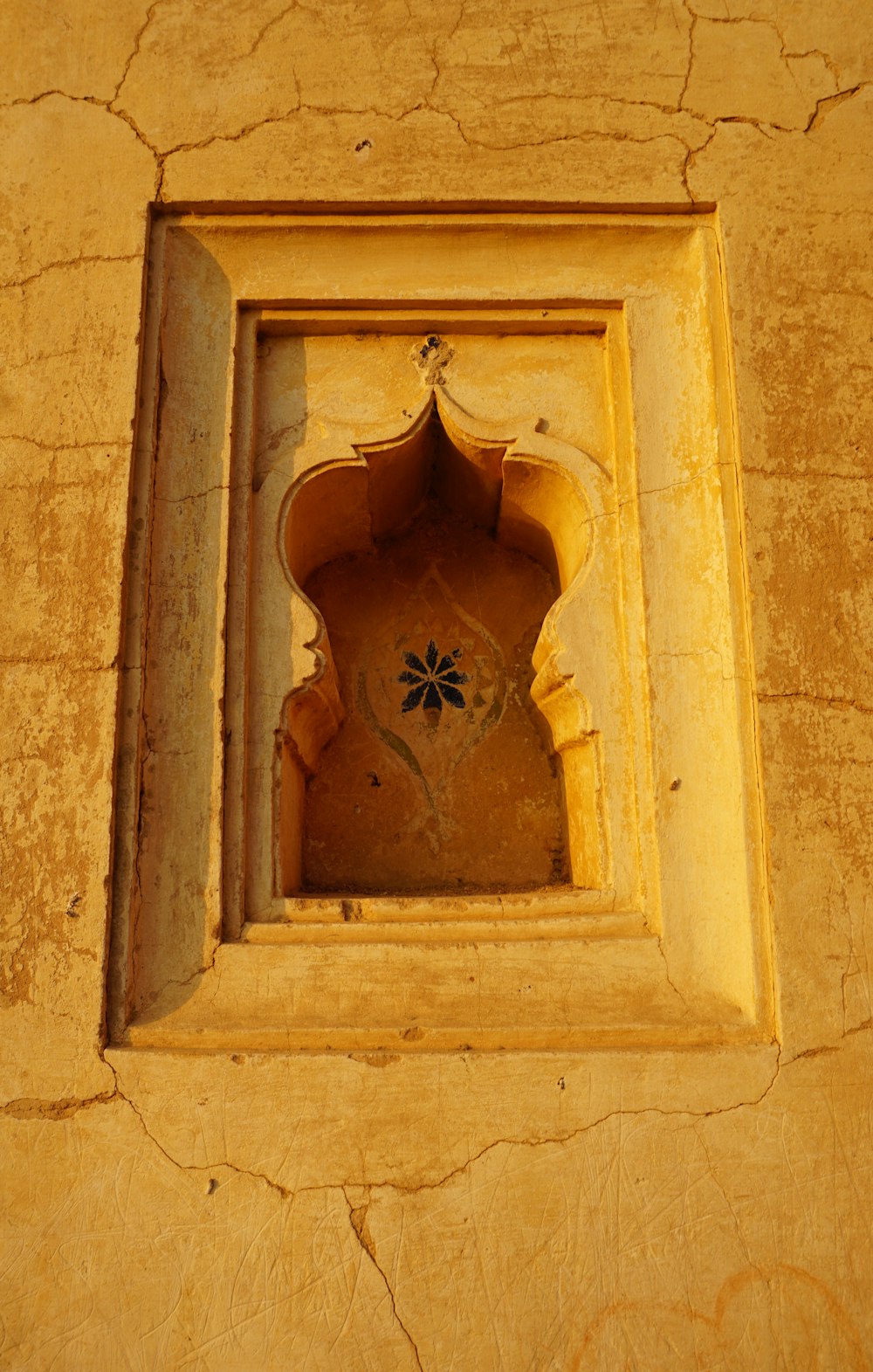 a window in a wall with a flower in it