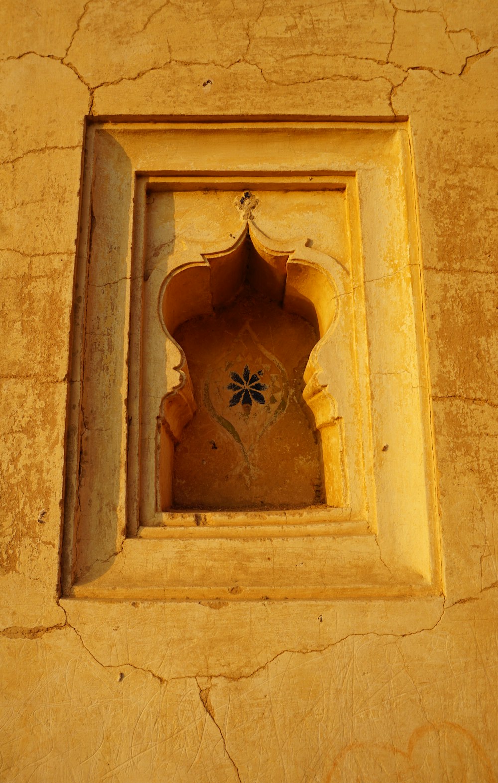 una ventana en una pared con una flor en ella