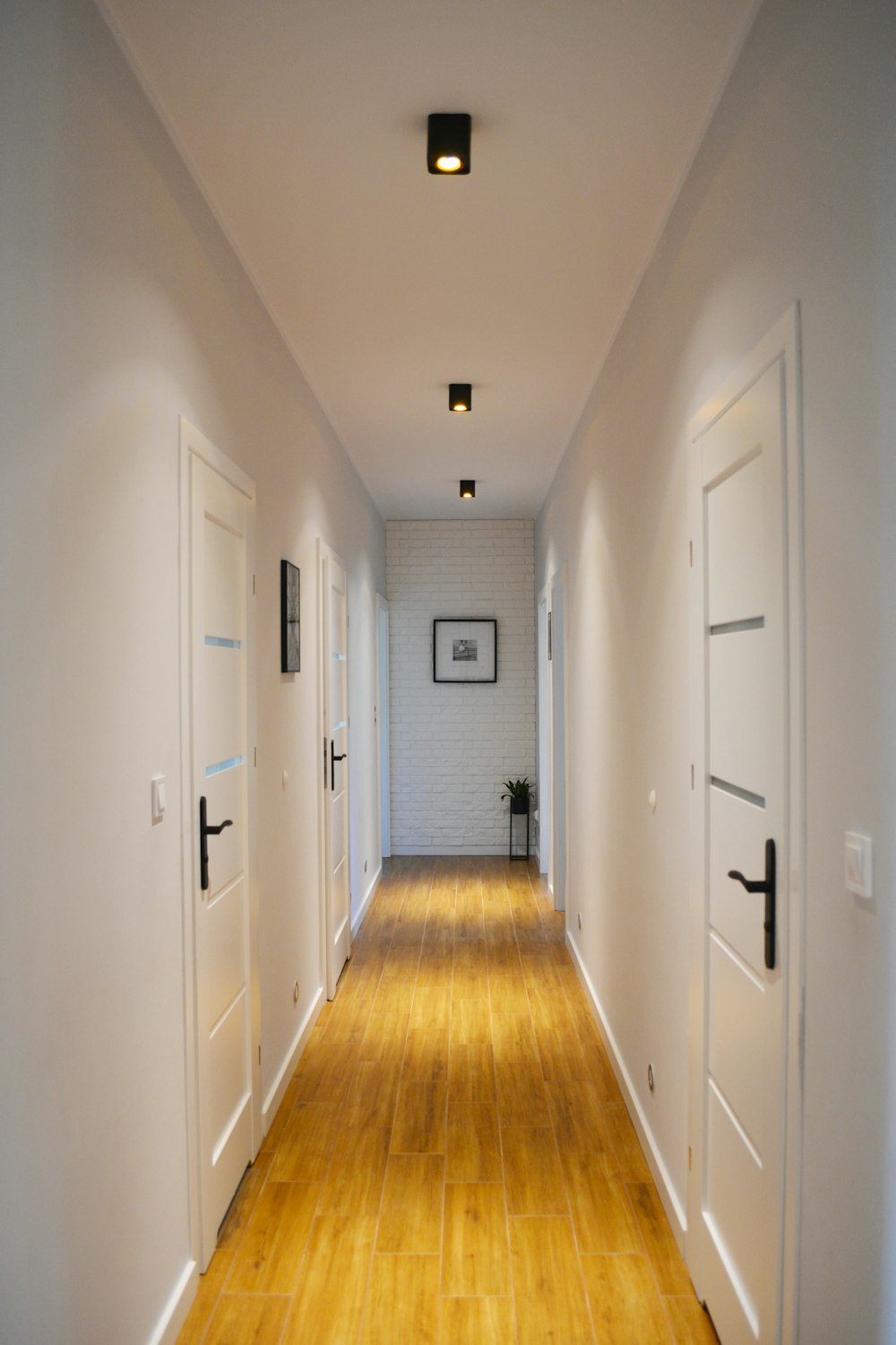 a long hallway with white walls and wooden floors