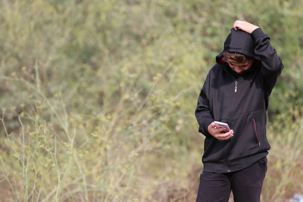 a man standing in a field looking at his cell phone