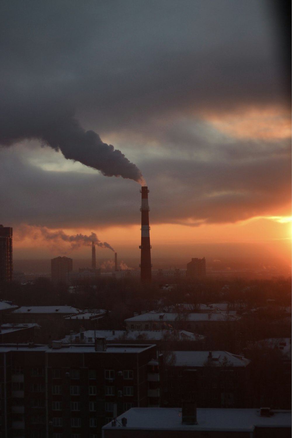 a smokestack emits from a factory at sunset