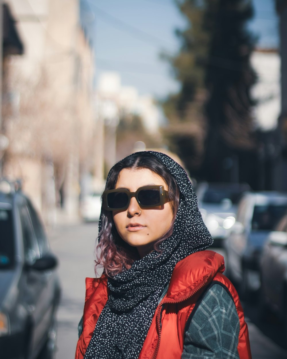 a woman wearing sunglasses and a scarf on the street