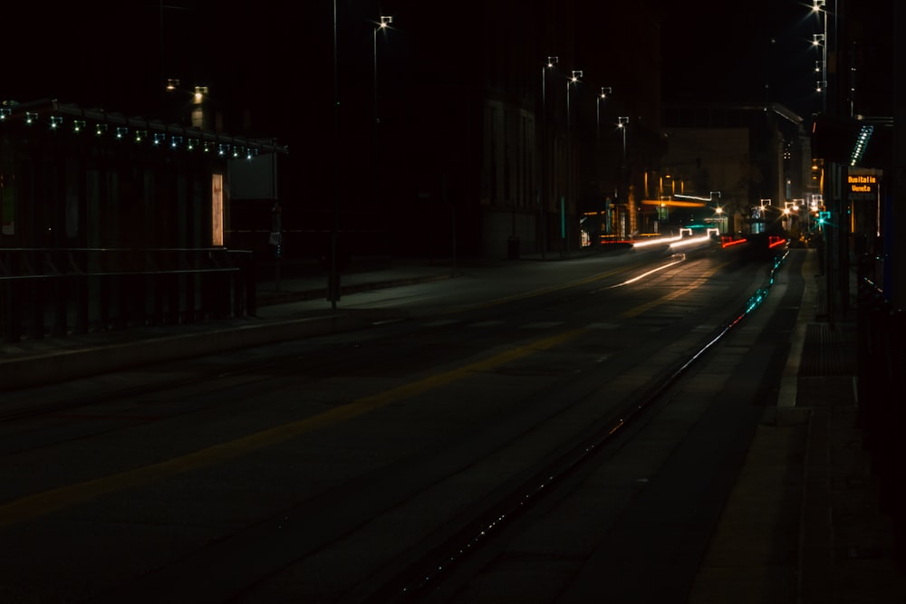 a city street at night with a train on the tracks