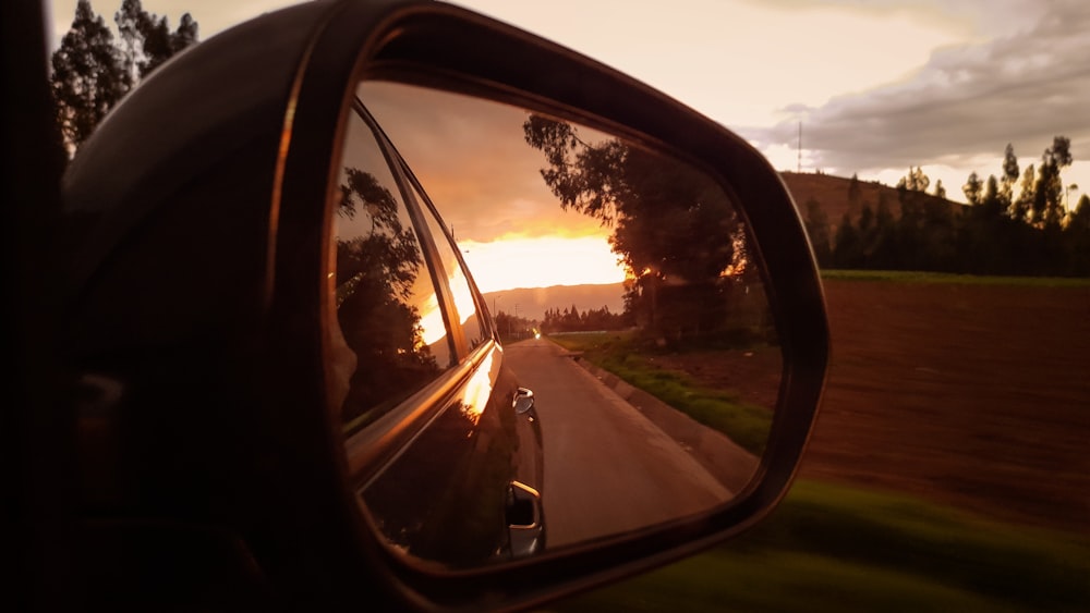 a car's rear view mirror reflecting a sunset