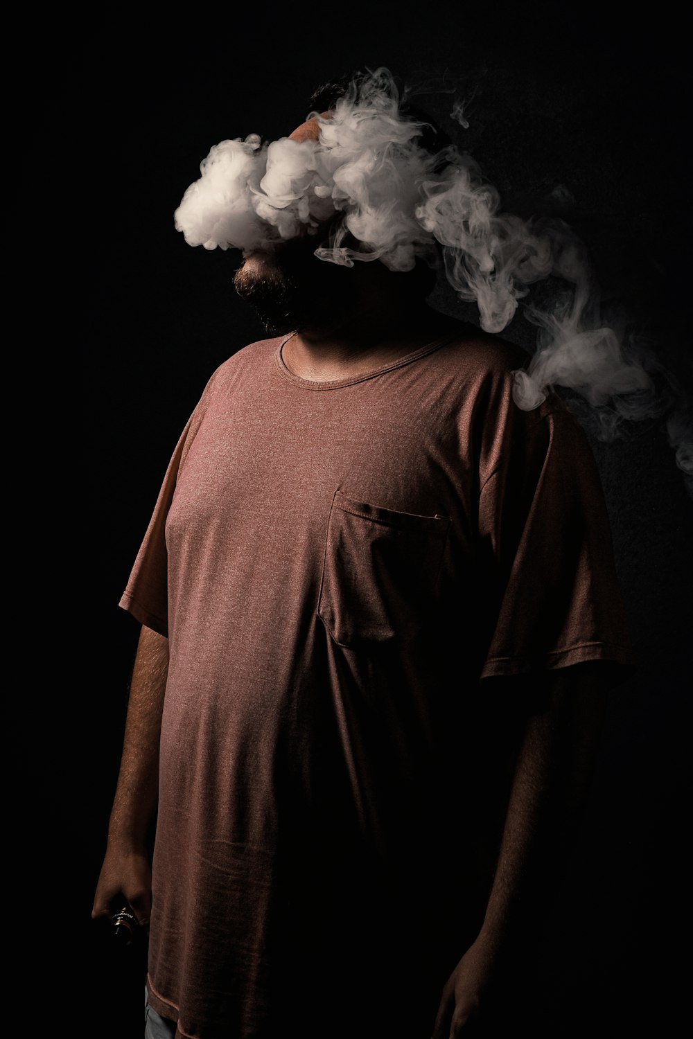 a man standing in front of a black background with smoke coming out of his mouth