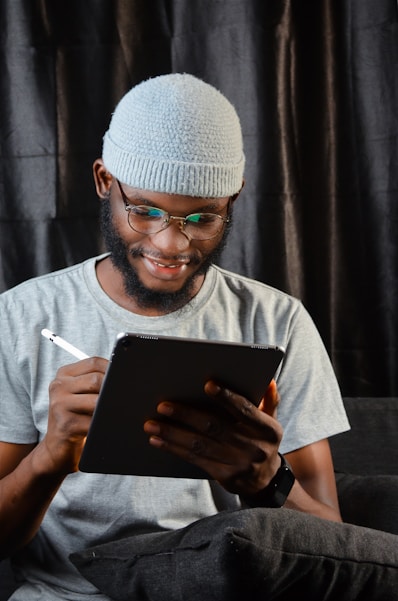 a man in a beanie is looking at a tablet
