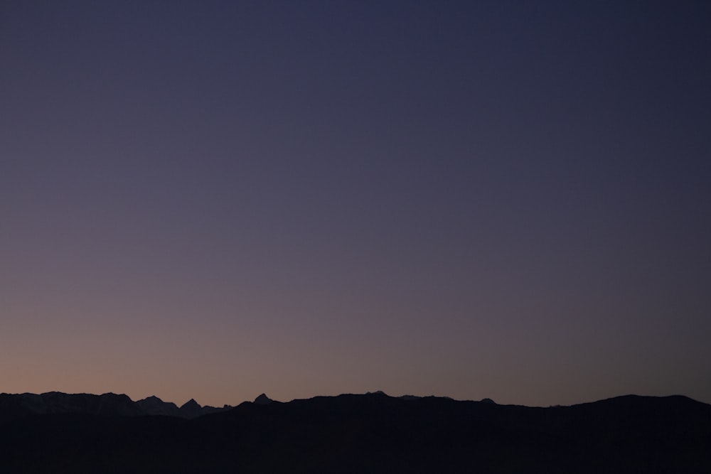 a plane flying over a mountain range at dusk