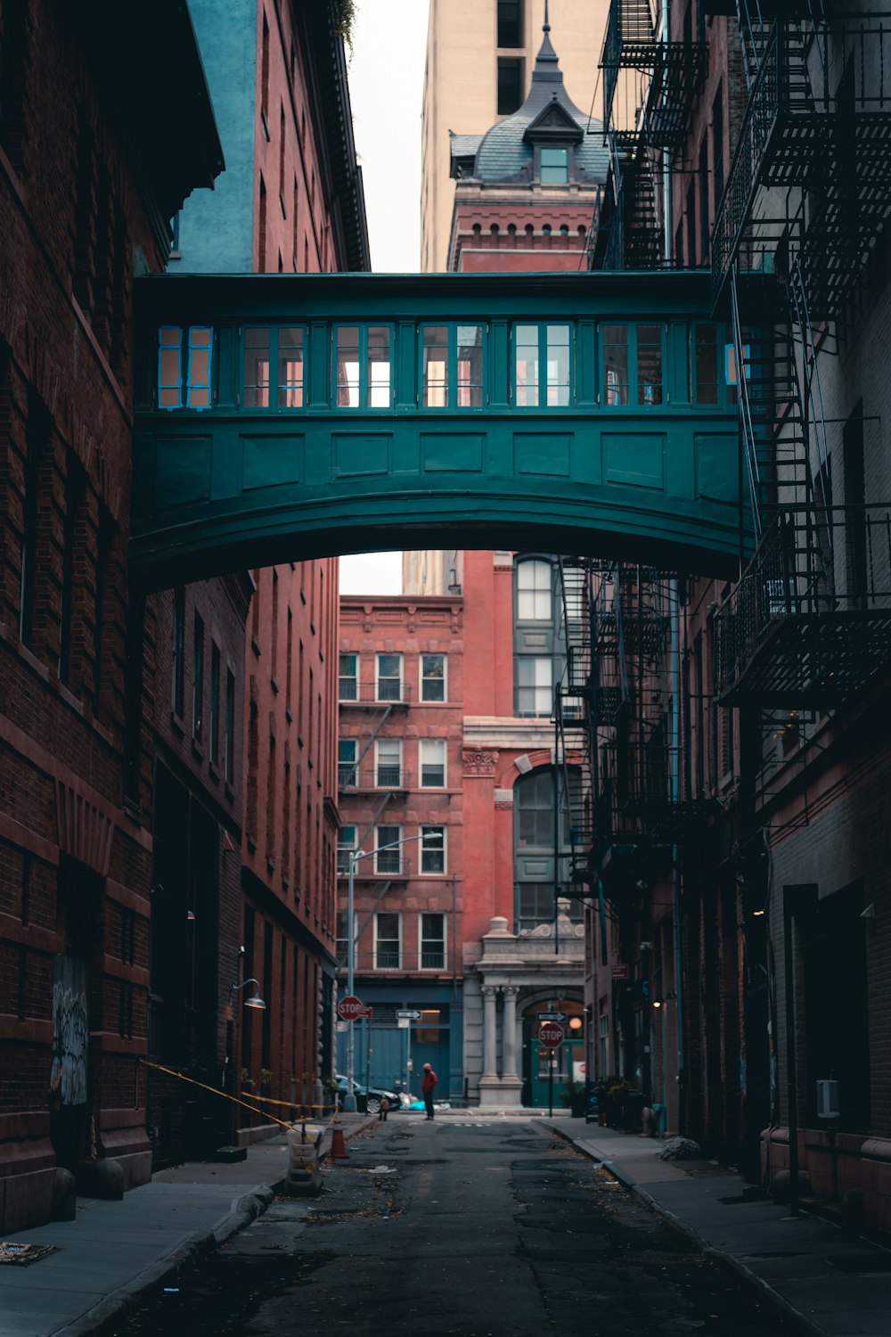 a narrow city street with a bridge over it