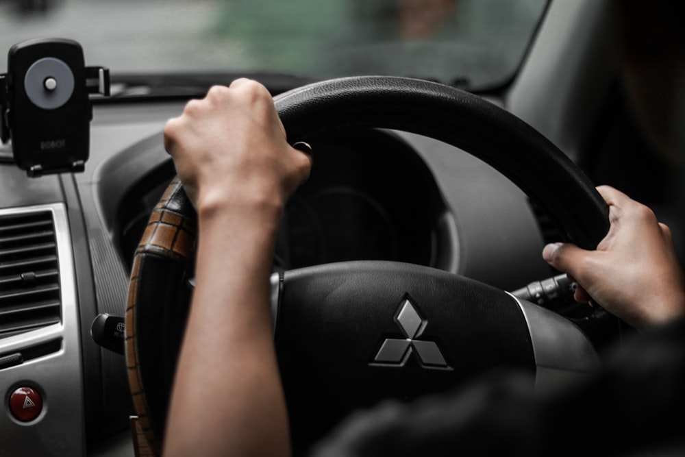 a person driving a car with a steering wheel