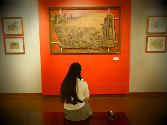 a woman sitting on the floor in front of a painting