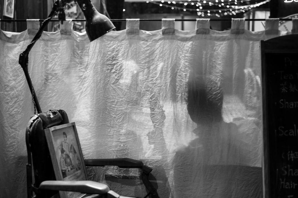 a black and white photo of a chair in front of a curtain