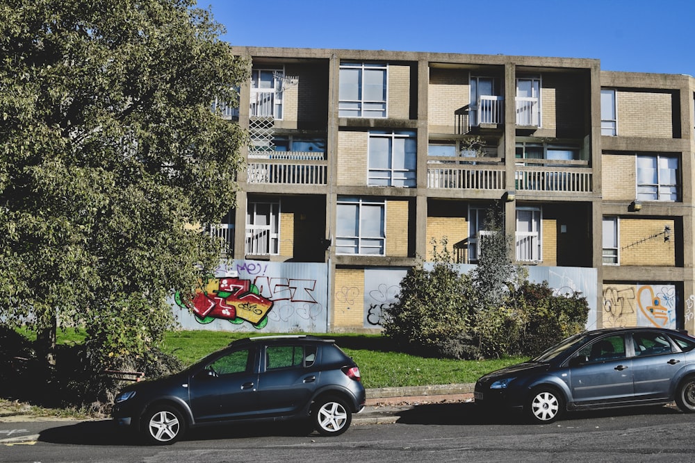 two cars parked in front of a building with graffiti on it