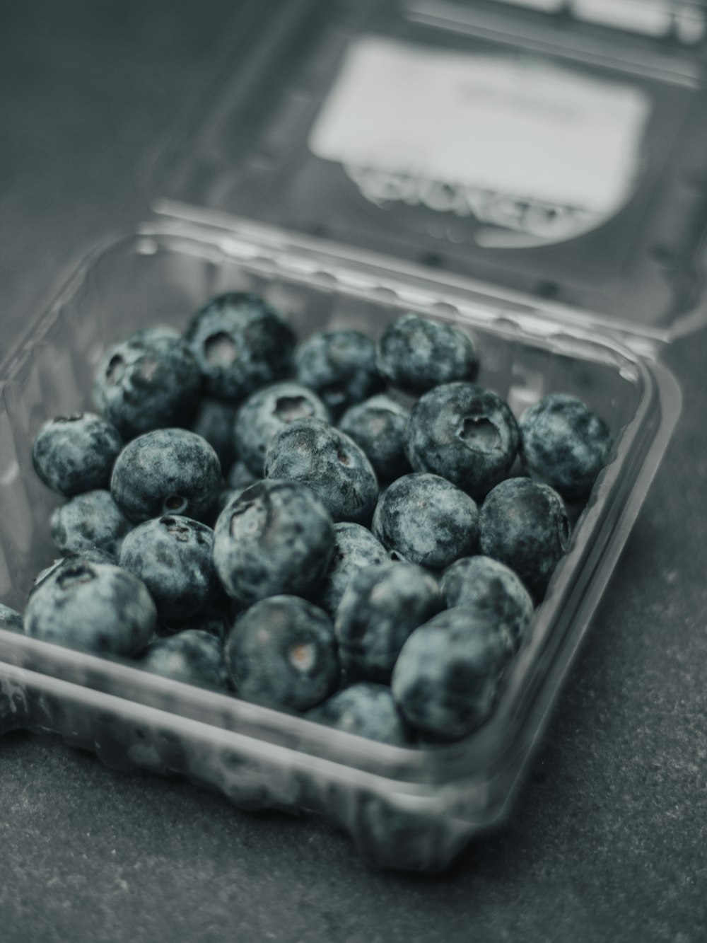 a plastic container filled with blueberries on top of a table