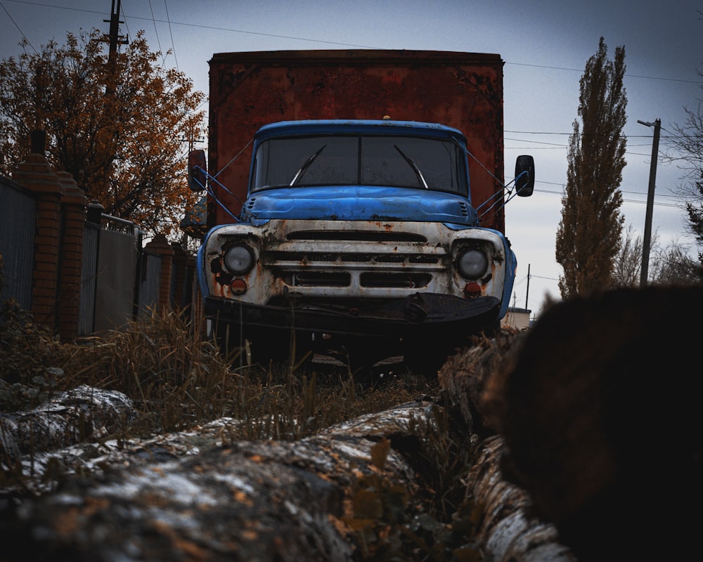 an old blue truck is parked in a field