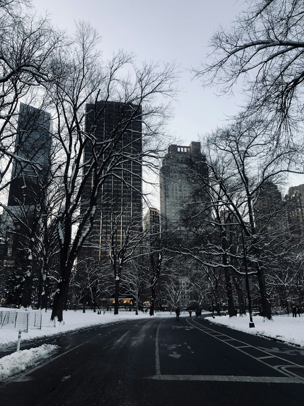 a snowy street with tall buildings in the background