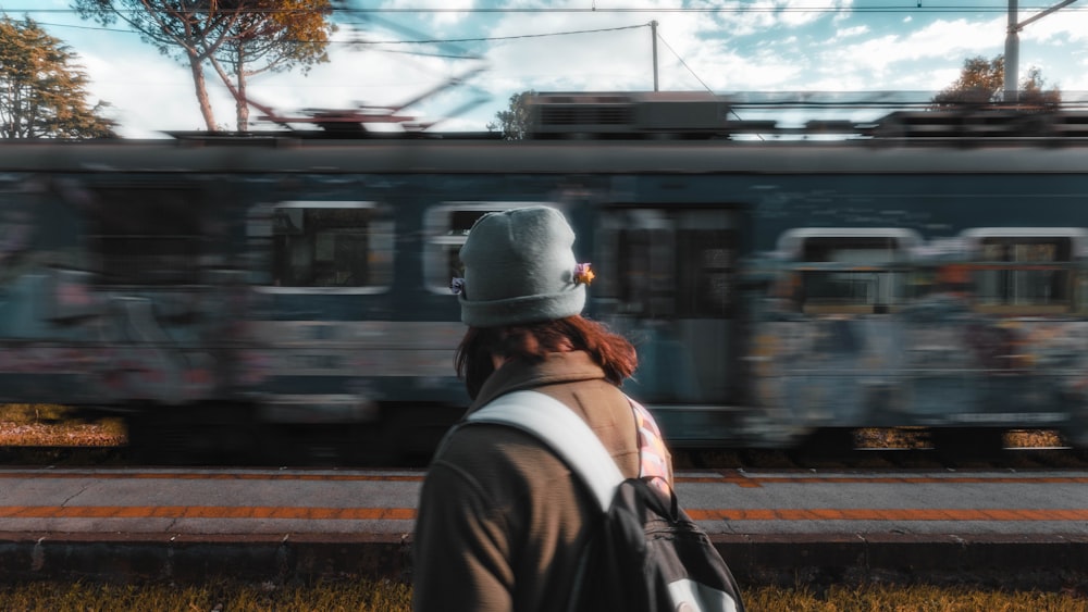 a person with a backpack is looking at a train