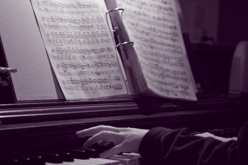 a person playing a piano with sheet music on it