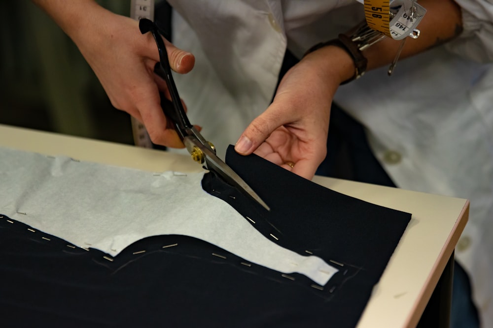 a person cutting a piece of fabric with scissors