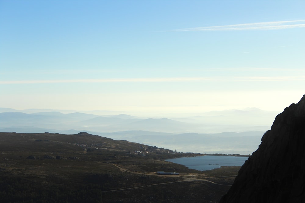 a man standing on top of a mountain next to a lake