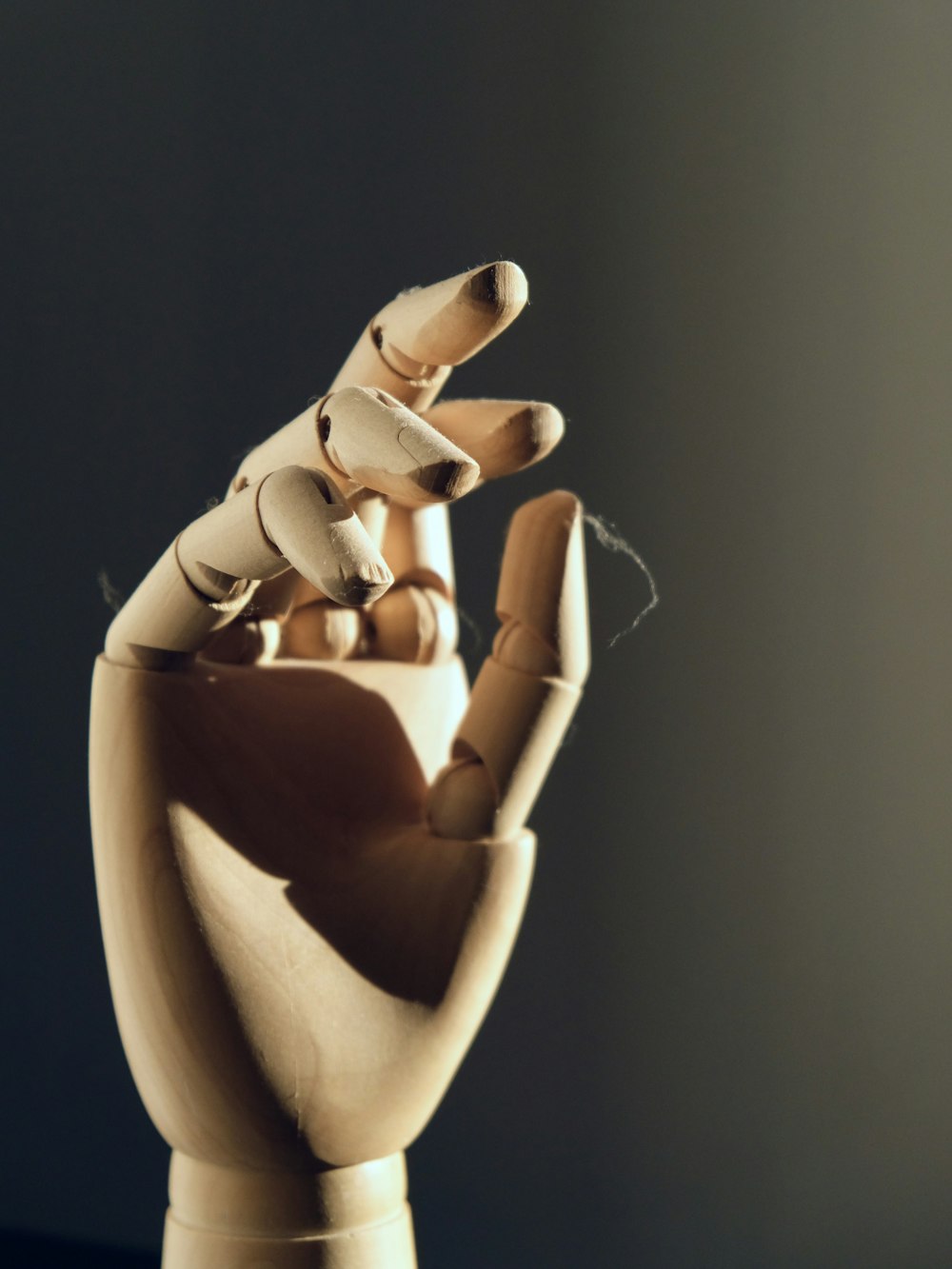 a wooden sculpture of a hand holding a group of wooden dolls