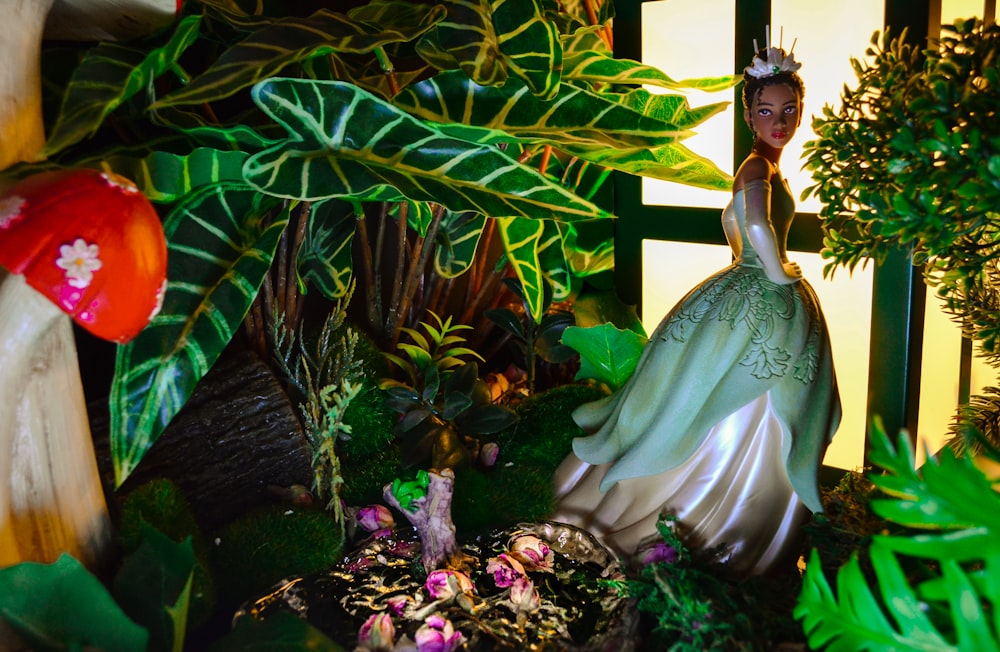 a statue of a woman in a green dress surrounded by plants