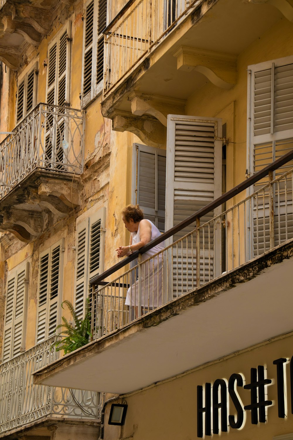 a woman standing on a balcony next to a building
