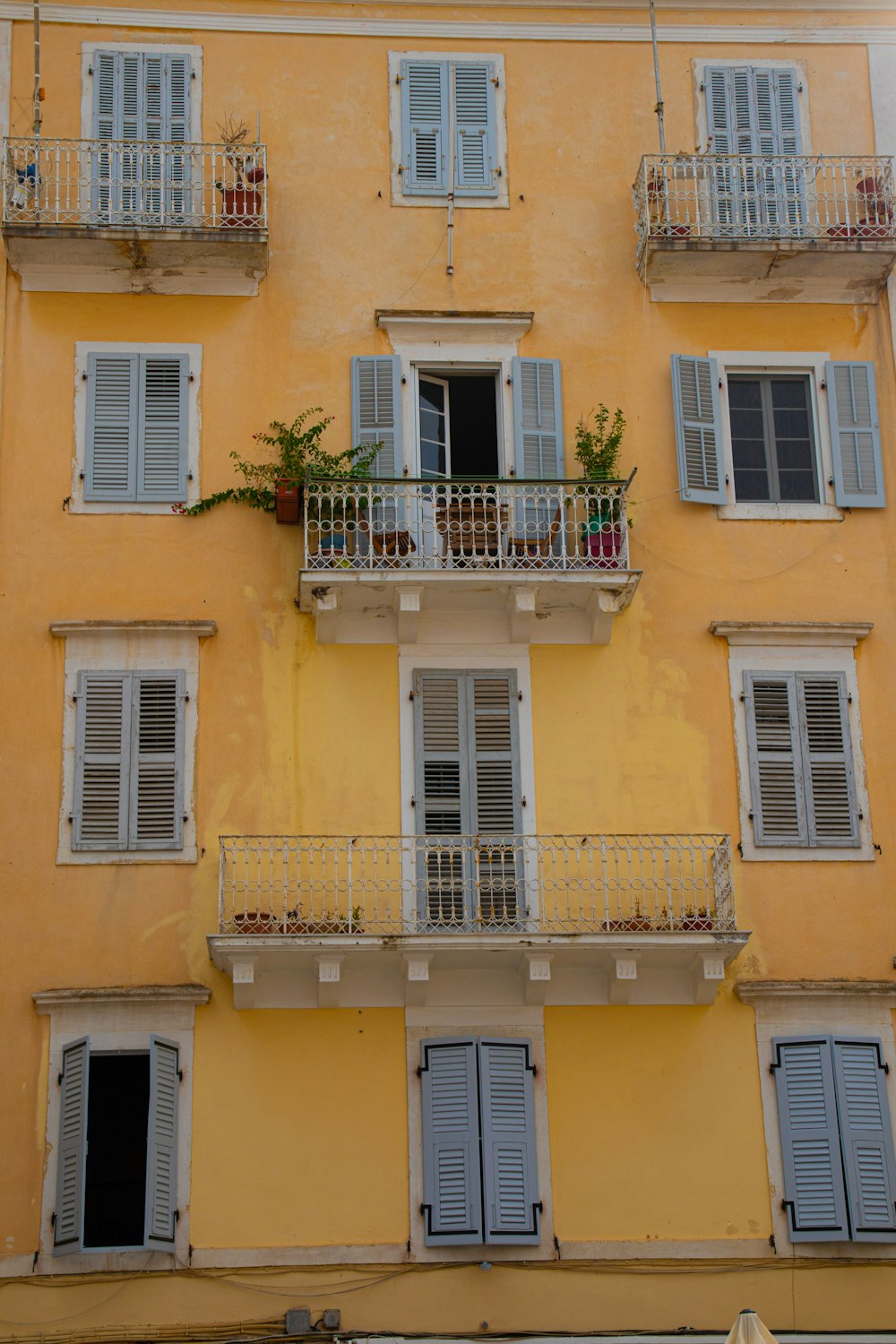 a tall yellow building with balconies and windows