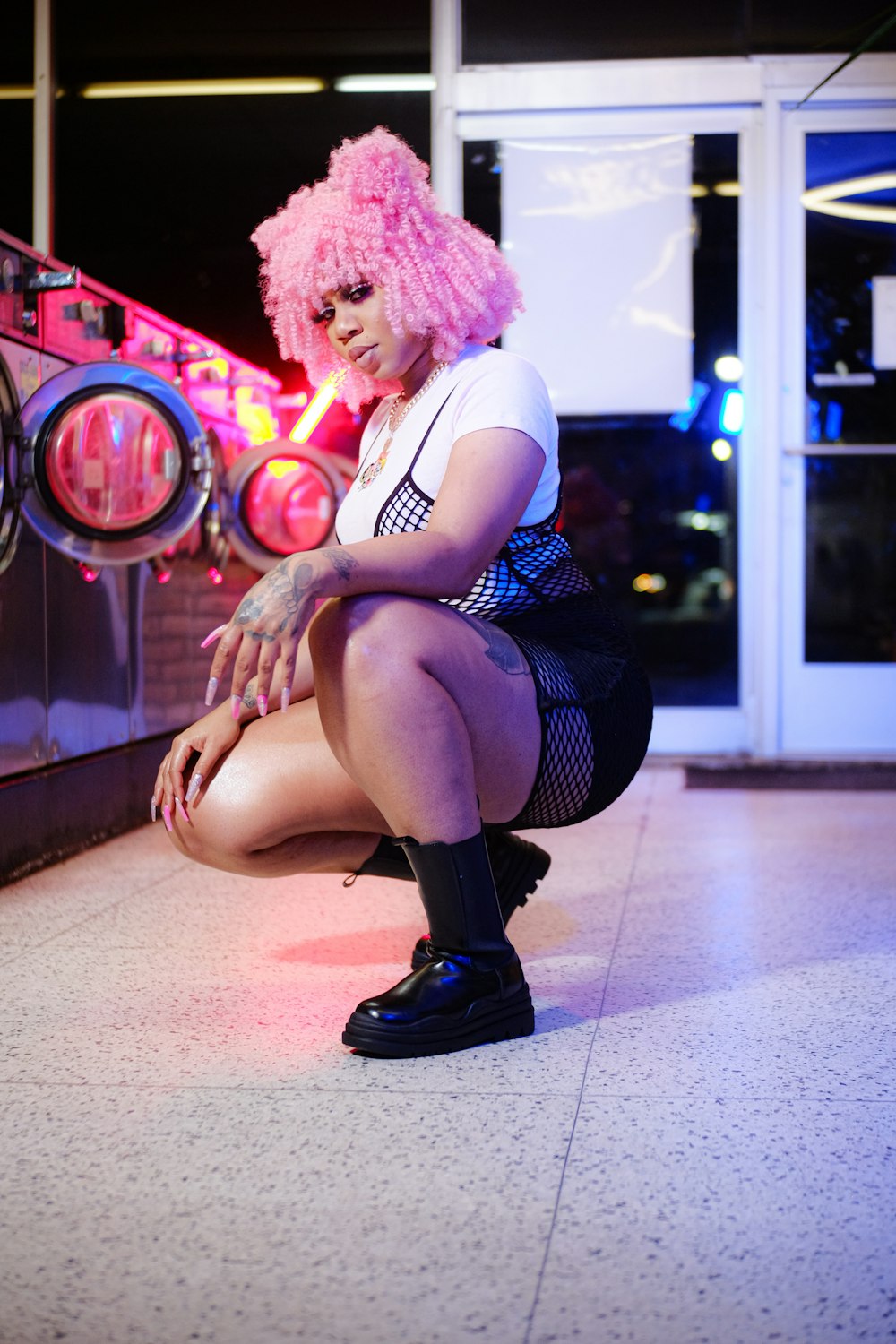 a woman with pink hair is sitting on the ground