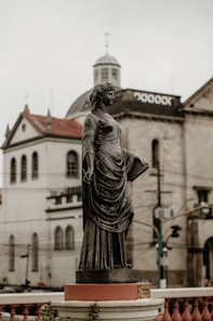 a statue of a woman standing in front of a building