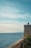 a person sitting on a ledge overlooking the ocean