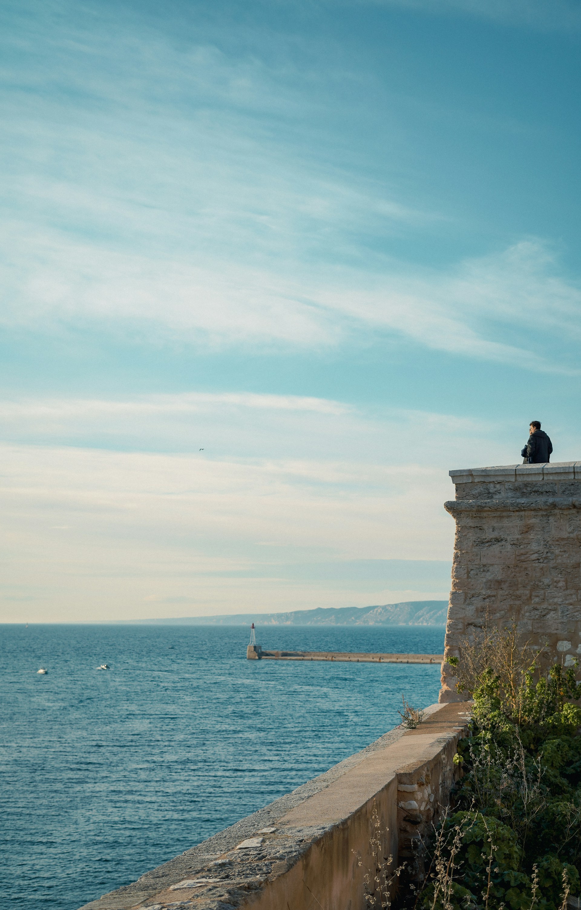 a person sitting on a ledge overlooking the ocean