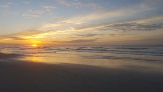 A serene sunrise over a beach with soft waves and gentle colors.