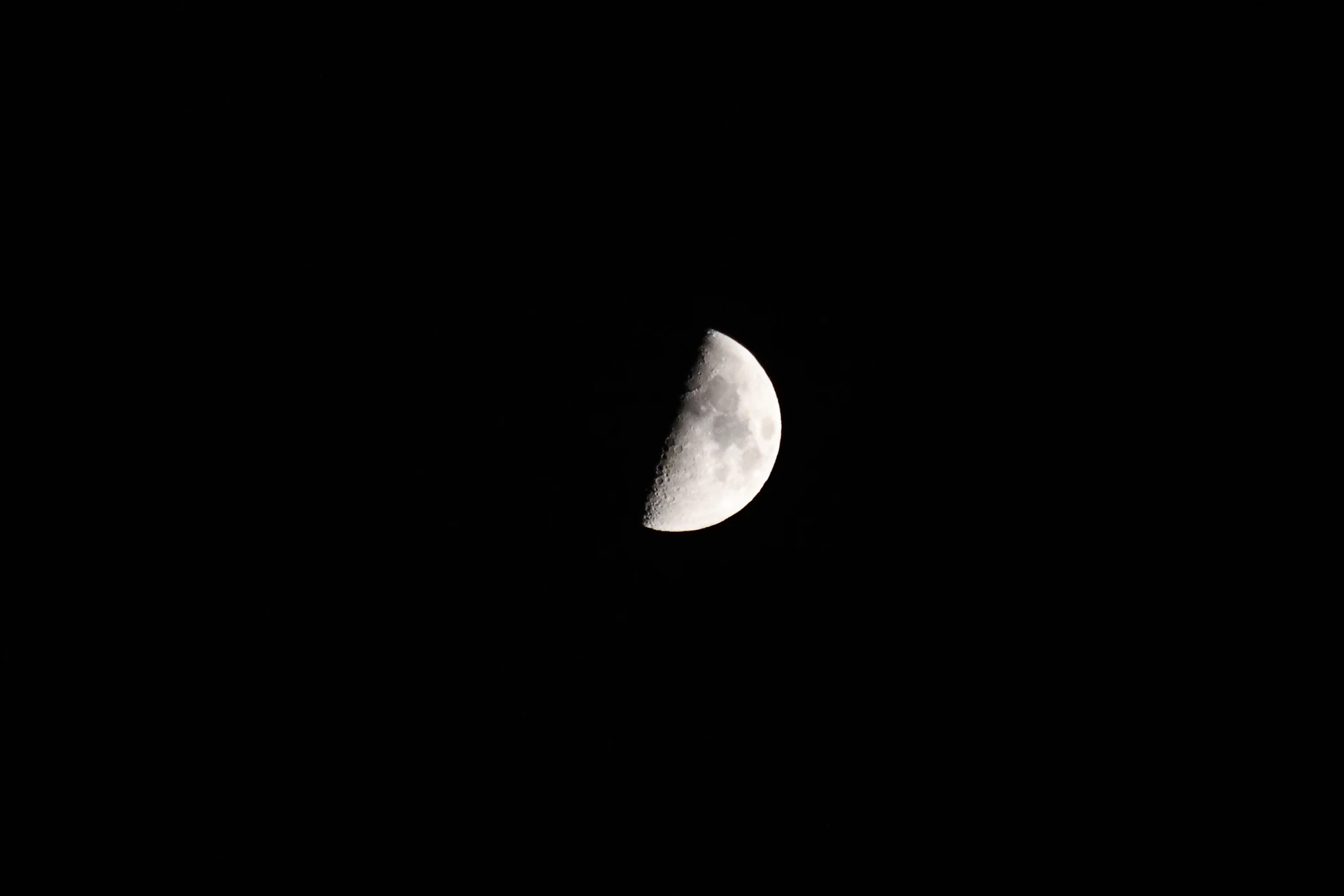 a half moon is seen in the dark sky