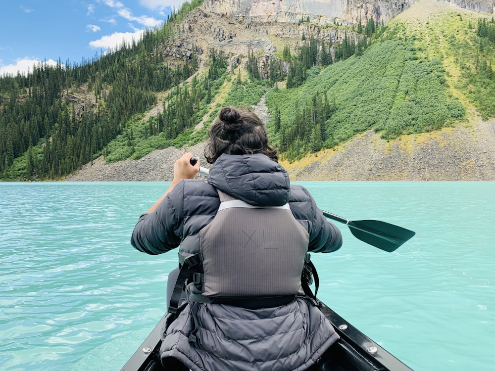 Una mujer remando en canoa en un lago de montaña