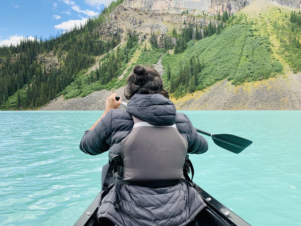 a woman paddling a canoe on a mountain lake